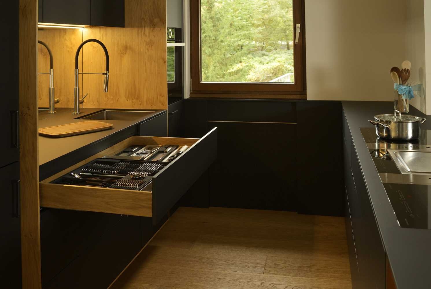 Moderne Küche in schwarz mit offener Schublade und schwarzer Fenix Arbeitsplatte